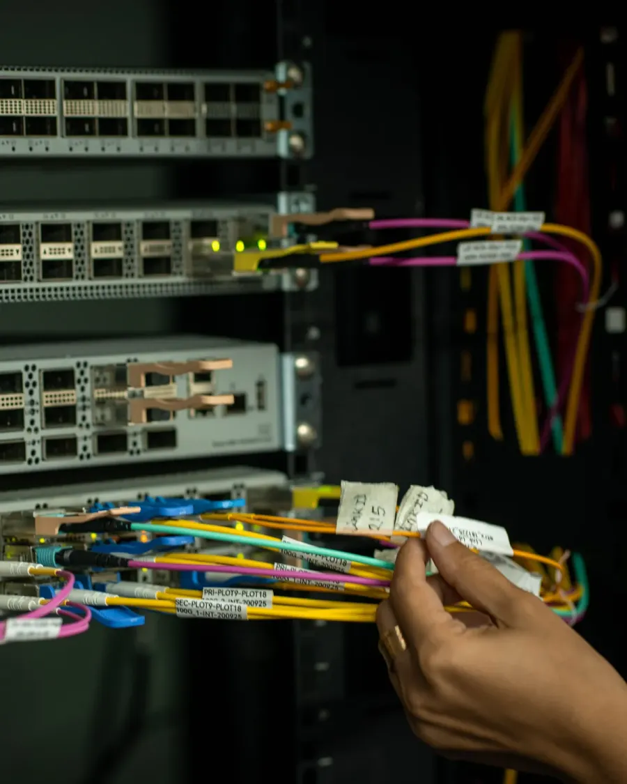 Técnico revisando un latiguillo de fibra etiquetado en un rack de comunicaciones que da servicio en Gijón